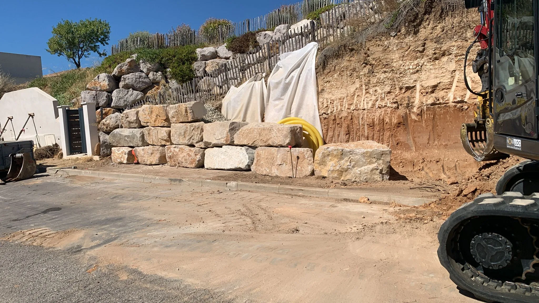 Réalisation d’un mur de soutènement pour un particulier à Mèze 07 Pose des premières pierres du mur de soutènement